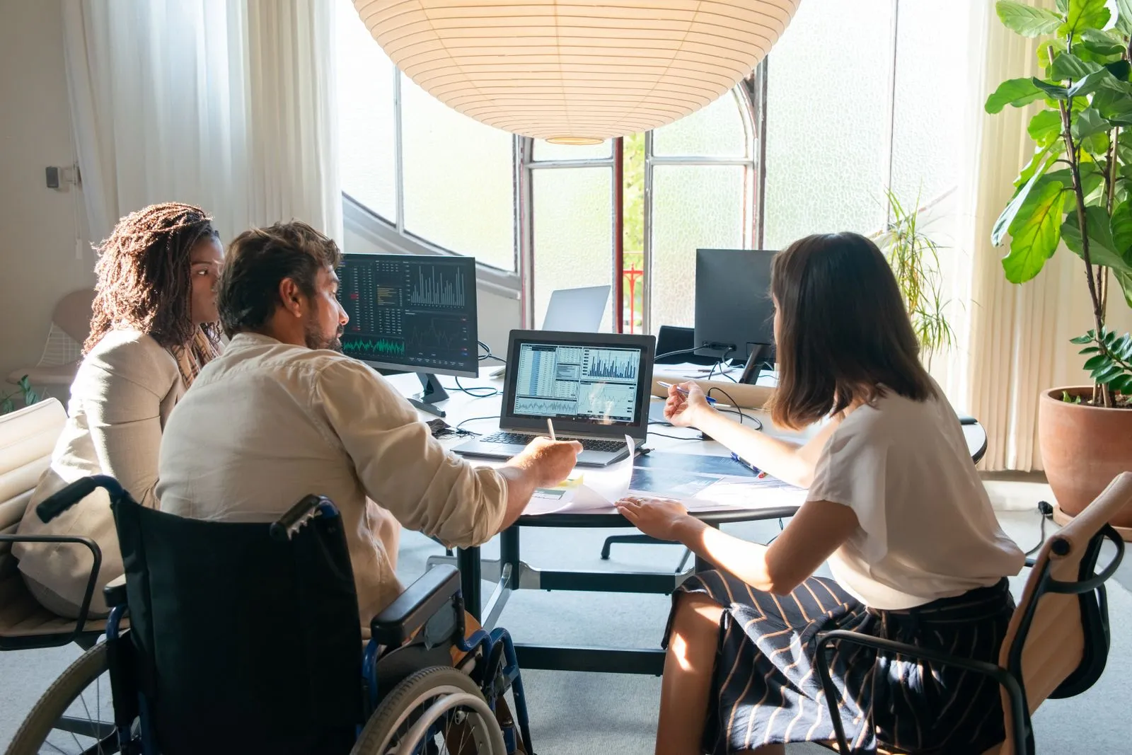 Team of diverse coworkers discussing charts and graphs at a bright, modern office table.